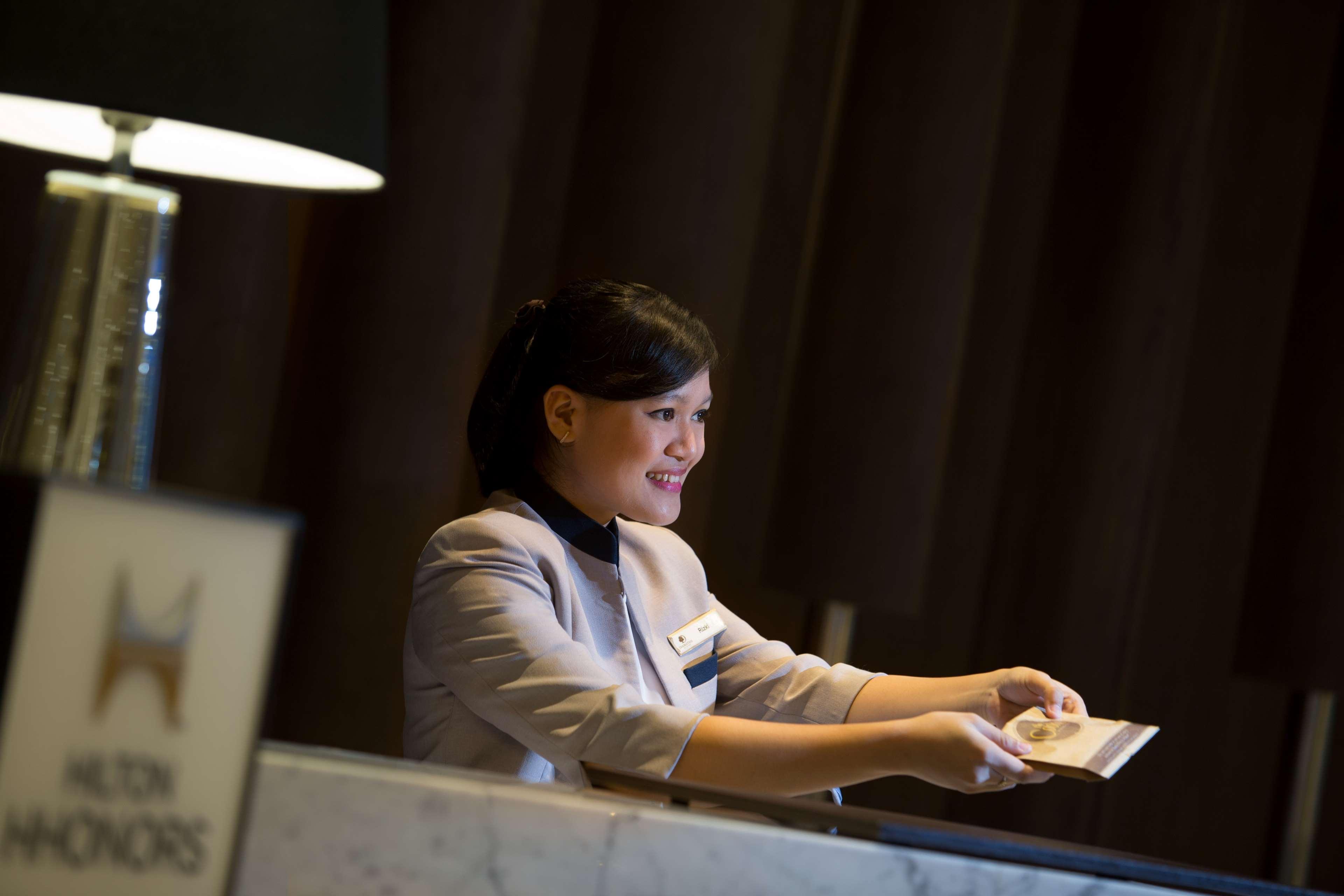 雅加达希尔顿逸林酒店 - 迪本尼格罗 外观 照片 A hotel receptionist at work